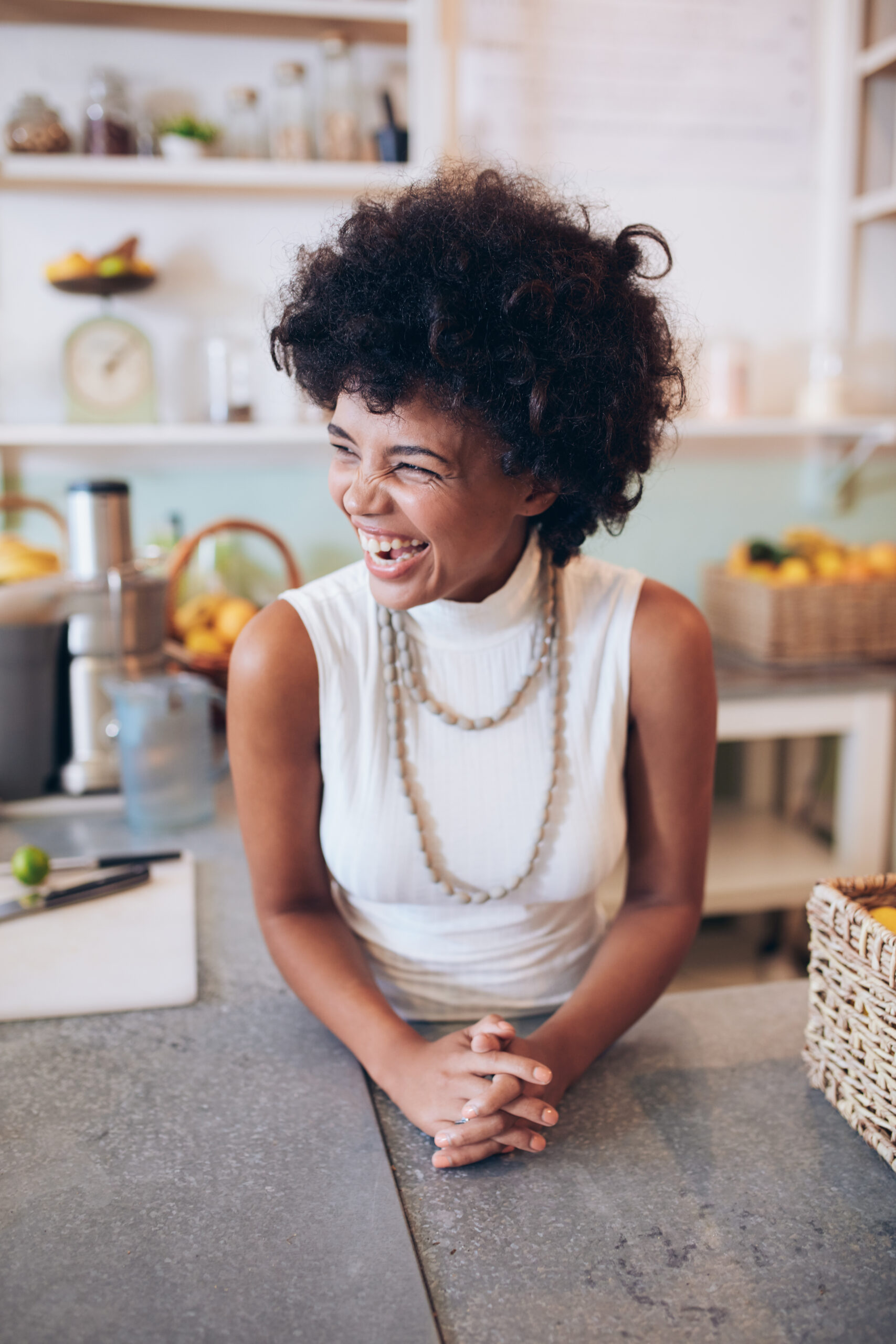 Portrait of cheerful young female standing behind counter. Successful juice bar owner looking away and smiling.