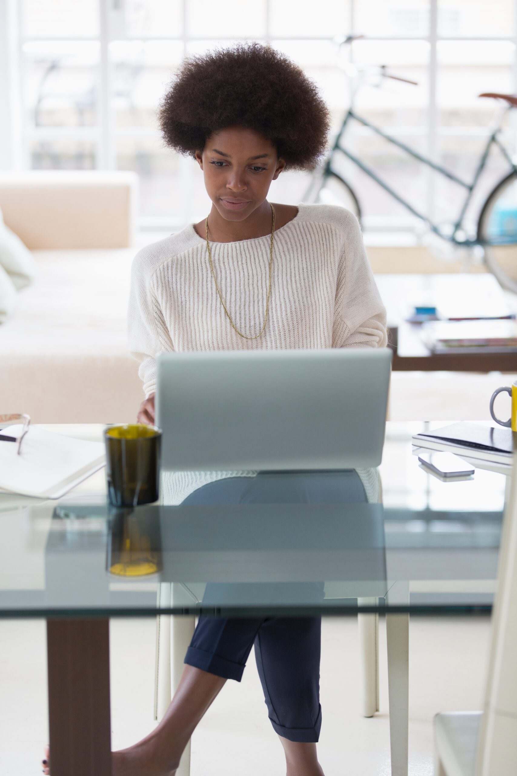 Young woman with afro working from home at laptop