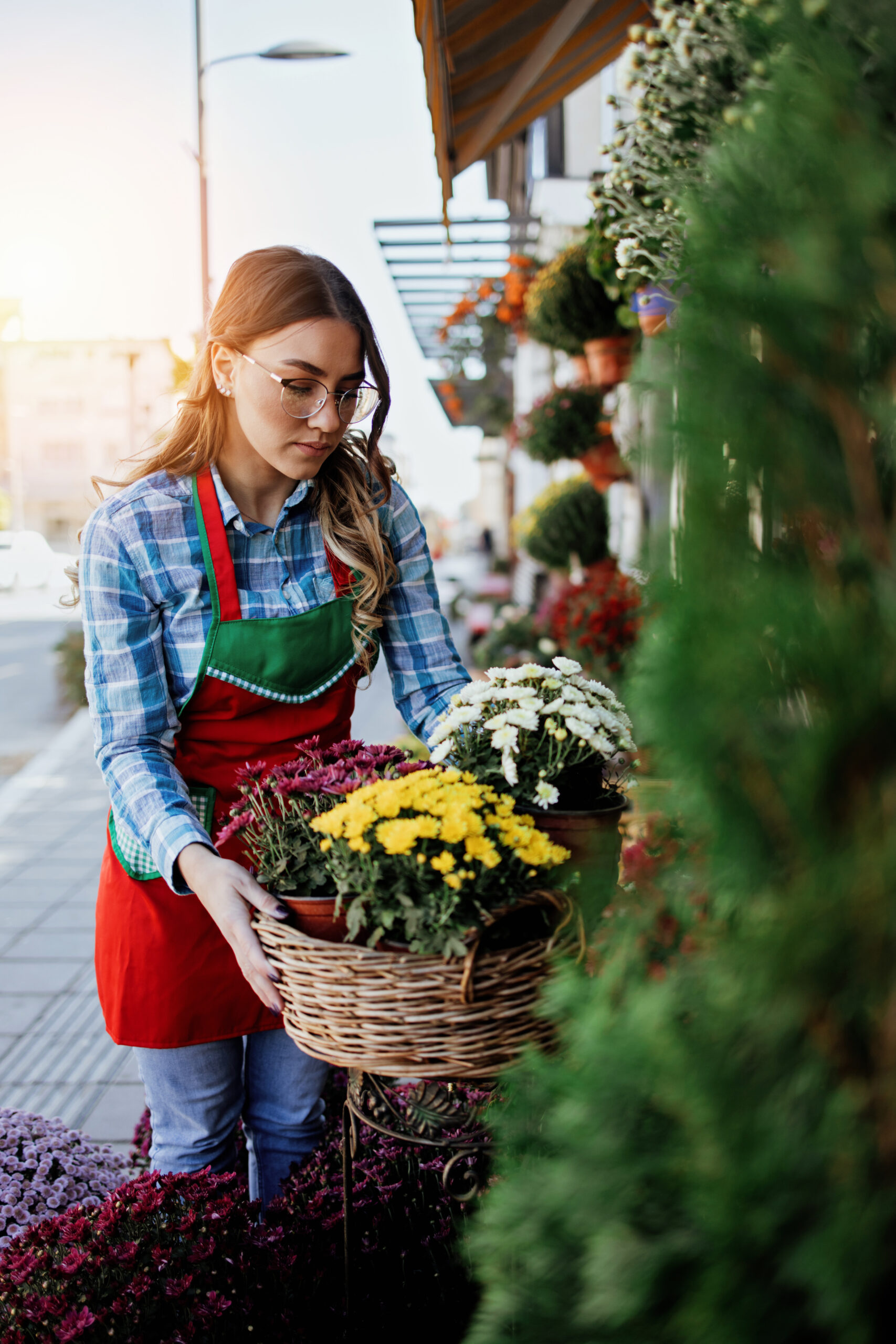 Young adult woman working in city street flower shop or florist. Small business concept.